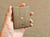 En hand håller en liten Motorola-enhet med träbaksida.